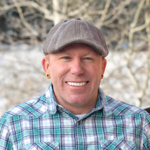Portrait of Kiel Sprague in a plaid shirt with snowy background and a fence