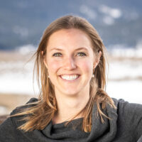 Adventuresmith expert Lauren smiling on a sunny day with her hair down and earrings on