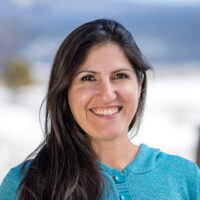 adventuresmith explorations adventure specialist leslie camacho wearing a turquoise shirt smiling on a sunny day with snow in the background