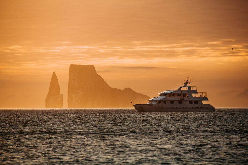 A Galapagos cruise yacht seen from its port side at sunset by Kicker Rock 