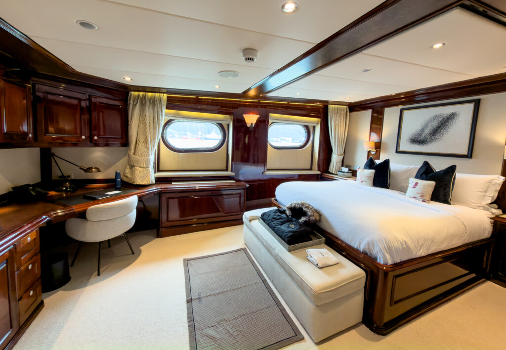 Category III Suite Cabin 203 aboard Aqua Lares. Porthole windows, rich mahogany wood walls, single bed, bench seat and desk. 