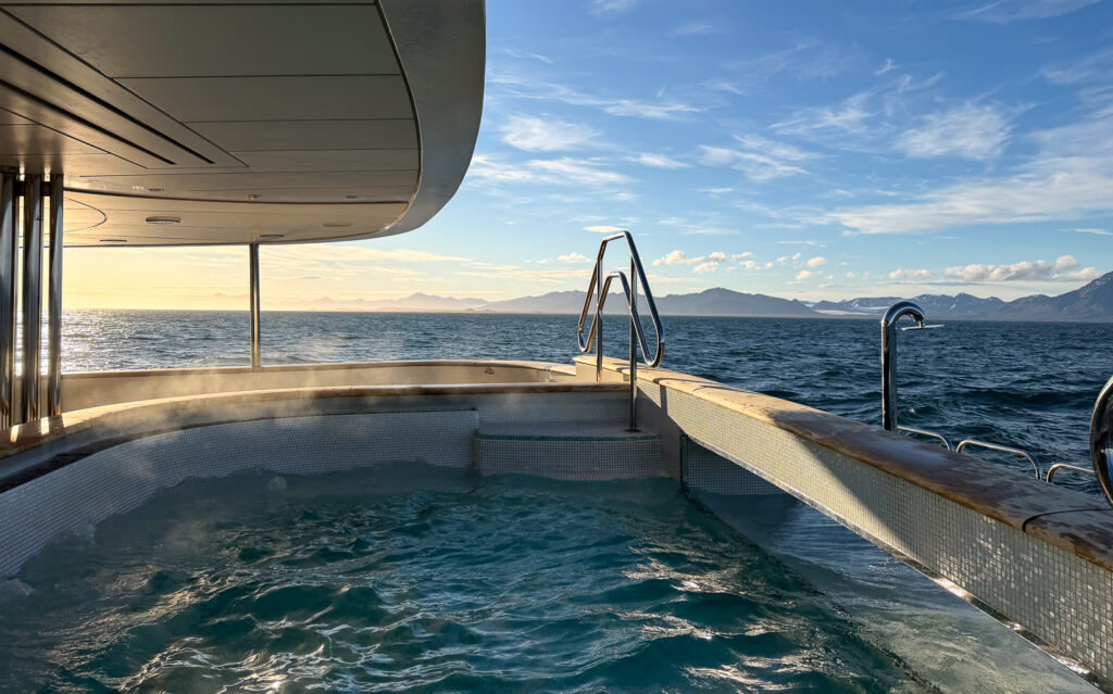 Steaming outdoor jacuzzi on the stern of Aqua Lares ship, on a blue sky day in Arctic Svalbard. 