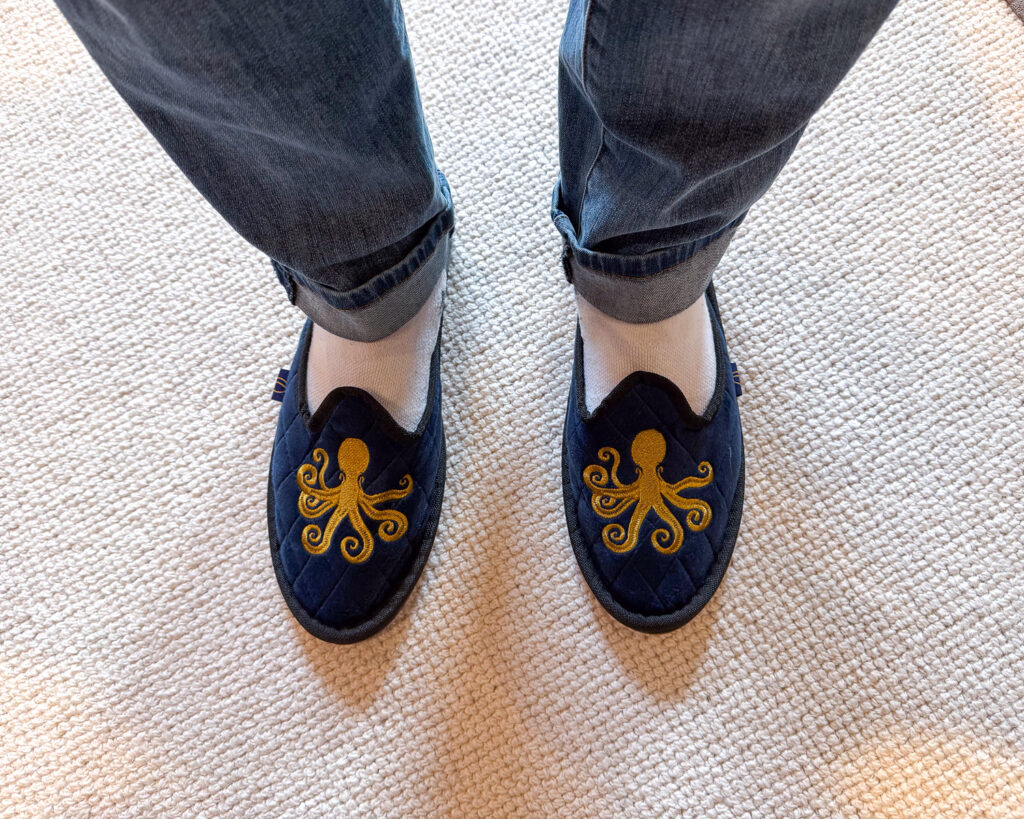 comfy blue and gold octopus-embroidered velvet slippers given to guests in their suite aboard Aqua Lares.