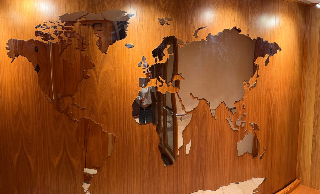 Inside Aqua Lares luxury icebreaker, a wooden wall  holds a mirrored art piece of the globe. 