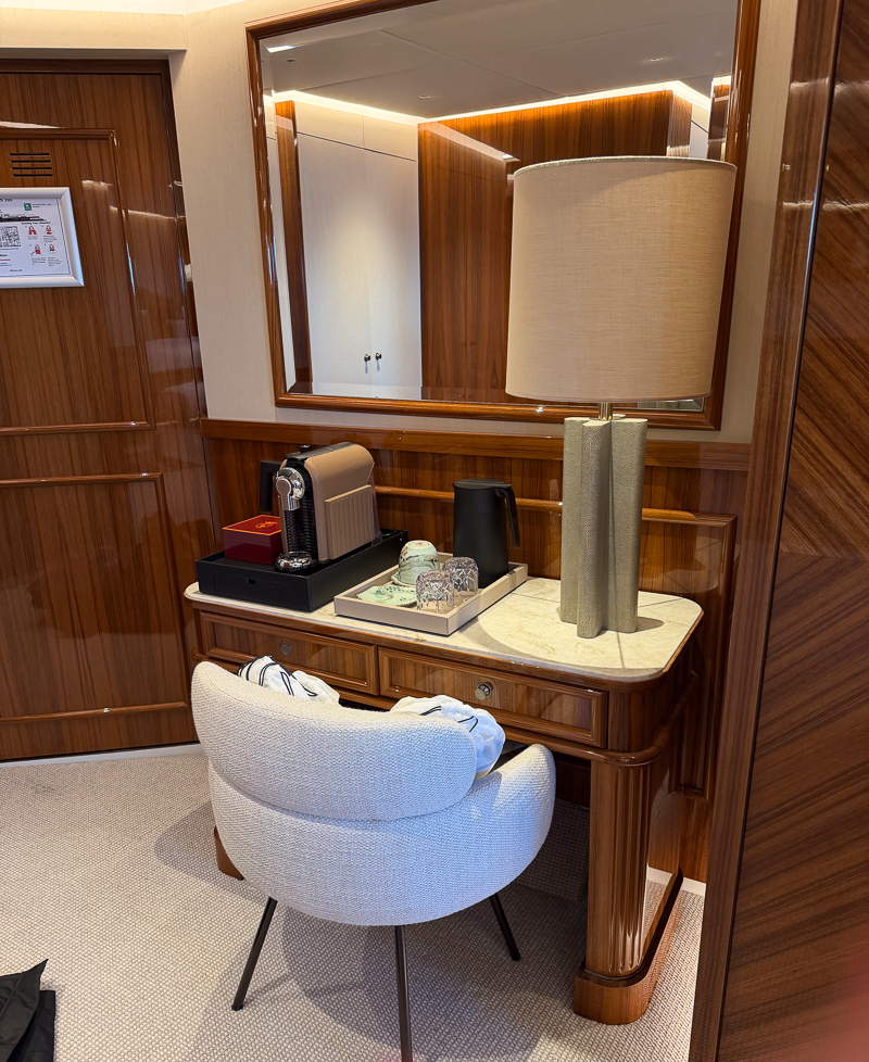 Inside the owner suite aboard Aqua Lares, a spacious sitting area and espresso machines, rich glossy wood mahogany walls. 