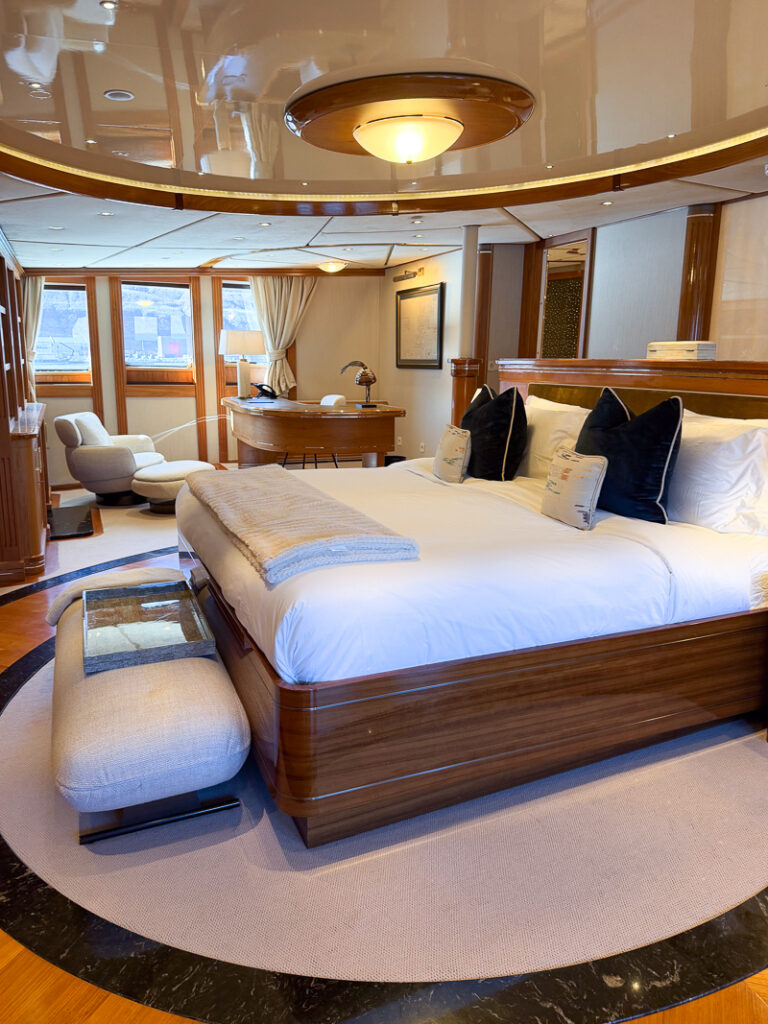 Owner suite aboard Aqua Lares, rich wood features, with black marble and white furniture throughout.