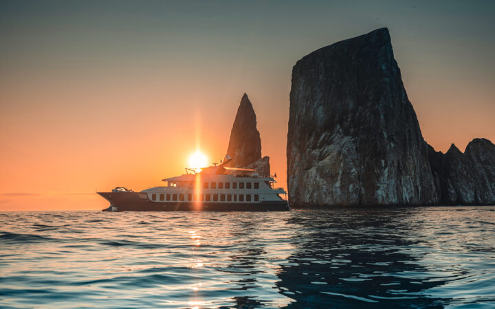 Luxury Galapagos cruise ship origin and theory at kicker rock at pastel sunset