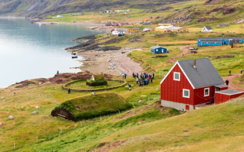 South Greenland Exploration cruise guests visit grassy seaside Brattahlio, Erik the Red's historic farm in Greenland.